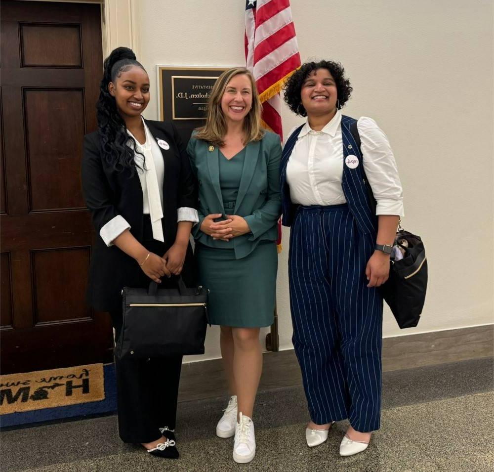 Two students stand alongside U.S. Representative